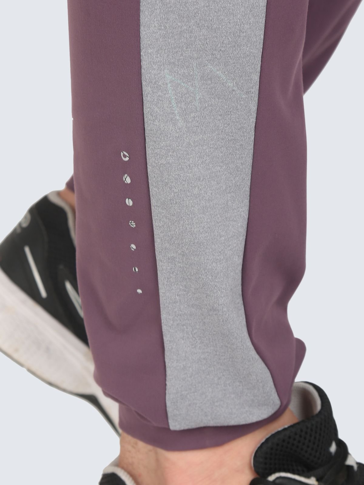 Close-up of lower leg showing plum jogger pants with grey side panel and ankle detailing
