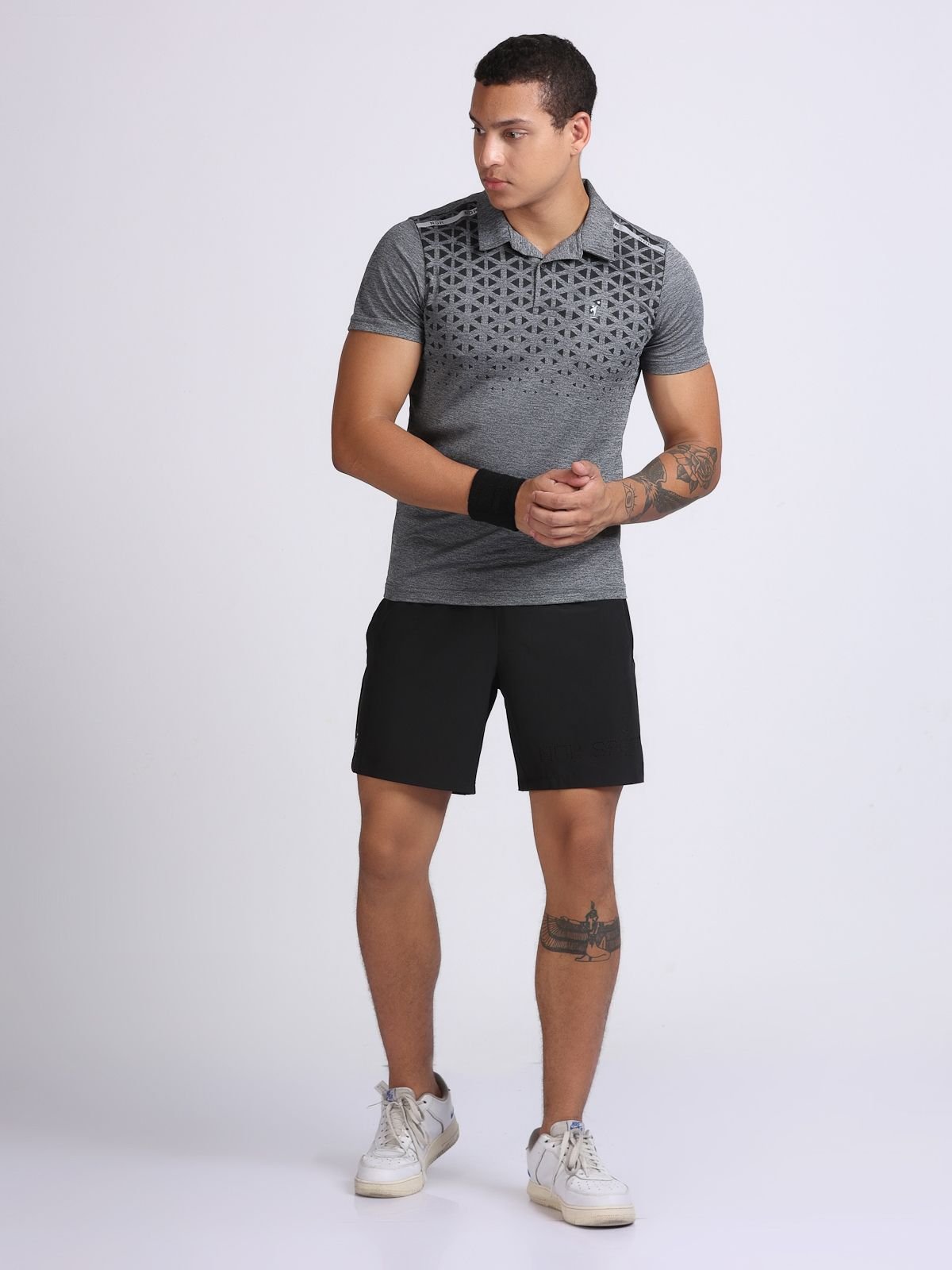 Male model in dark grey geometric-print polo T-shirt Milanz Illustrated and black shorts, walking pose