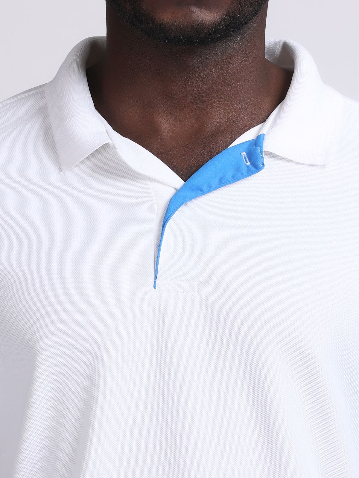 Close-up of the collar and bright blue contrast inner placket on a white Solid polo t-shirt of NDR SPORT.