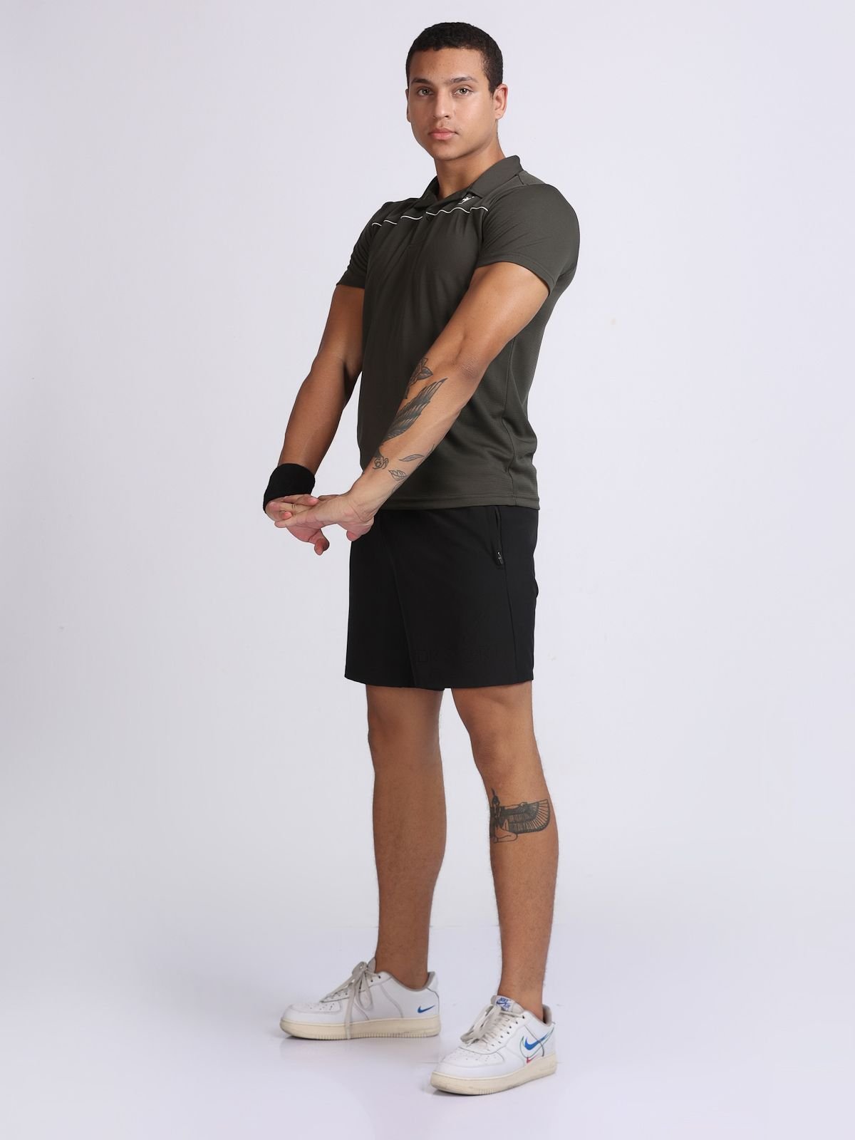 Male model in olive green sport polo tshirt doing full-body stretch pose
